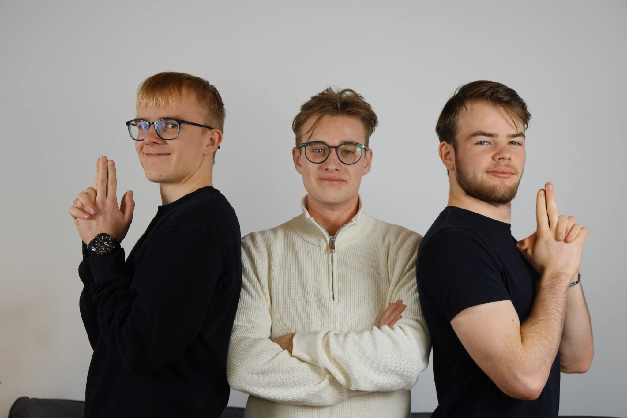 Luca Schackmann, Vincent Helmers and Lukas Laschinger, the founders of Itegro GmbH, standing in front of a white wall. Two of them make finger gun poses, the one in the middle has arms crossed.